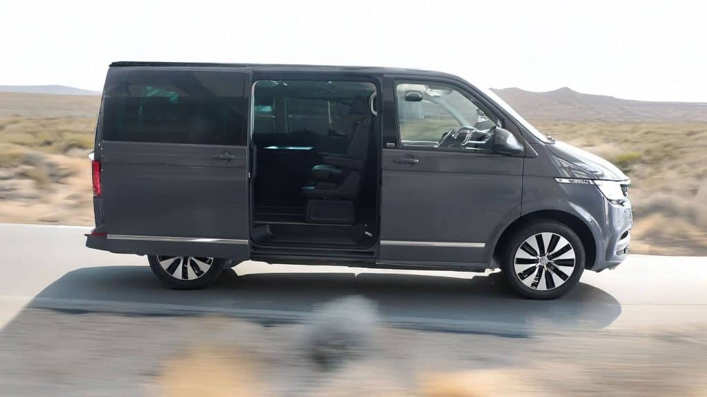 VW Multivan mit geöffneter Schiebetür auf Straße in Wüstenregion, Seitenansicht